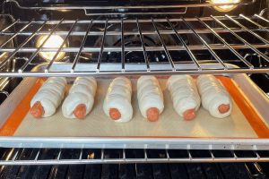 row of hot dogs in dough before baking