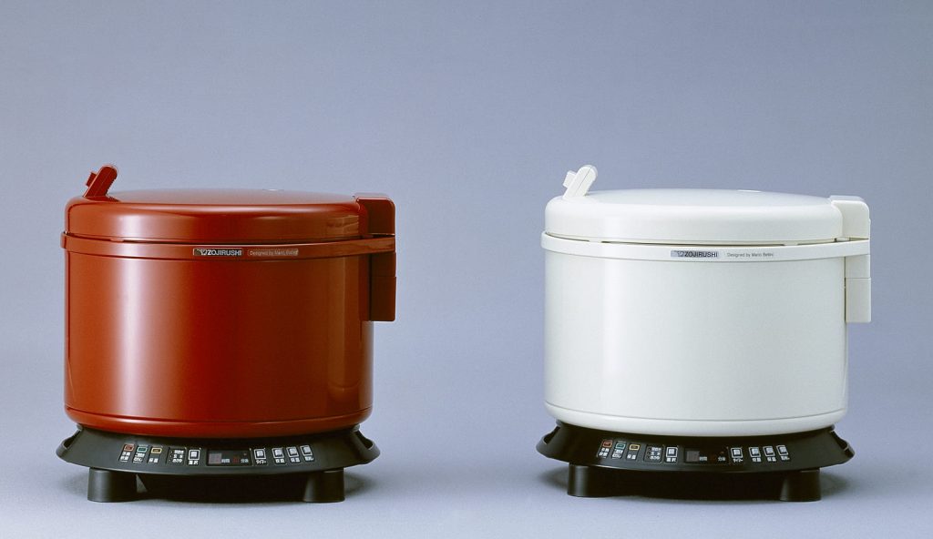 red rice cooker and white rice cooker in a grey background