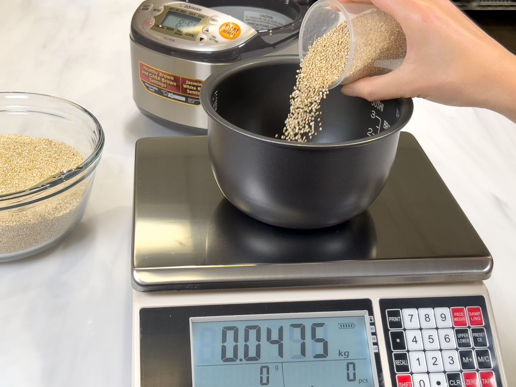 Adding quinoa to the rice cooker pan on the digital scale