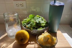 ingredients for green smoothie, fresh greens, lemon, pineapple and ice