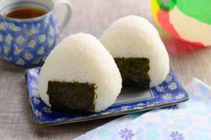 2 white onigiri with seaweed on the blue and white plate