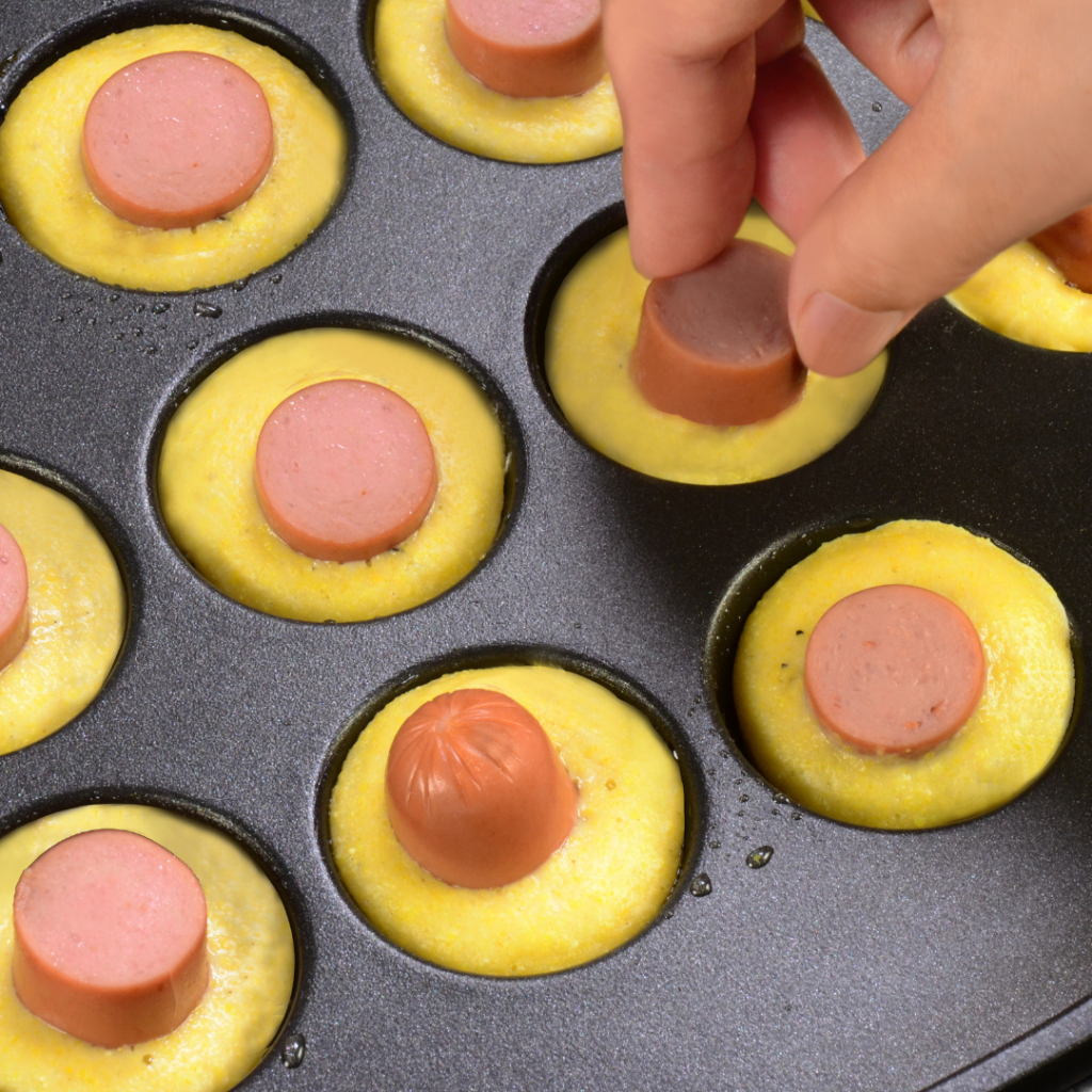 adding corn dog ingredients into takoyaki plate